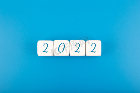 邀请函金融摄影照片_亮蓝色背景下白色玩具块上写的 2022 个数字，带有复制空间