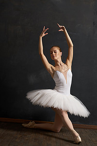 古典芭蕾舞摄影照片_穿着白色芭蕾舞短裙的女芭蕾舞演员表演优雅的舞蹈