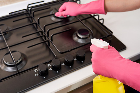 家务劳动摄影照片_用厨房用具、家居概念或卫生和清洁来清洁燃气灶。