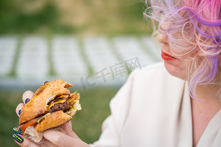 卷发的白种女人吃汉堡。