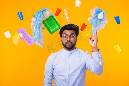世界环境日、塑料回收问题和环境灾难概念 — 印度男子在黄色背景下做出创意手势