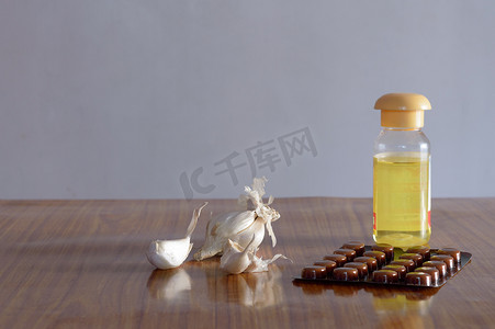木桌上的大蒜食品、油瓶和药丸。