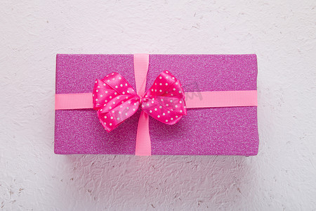 浅白色背景上的粉色闪亮礼盒，带粉色圆点弓顶视图