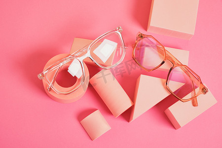 几何粉色讲台上的时尚眼镜、彩色背景、复制空间