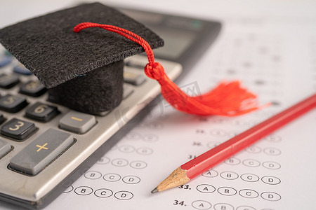 毕业间隙帽子和铅笔在答卷背景上：教育研究测试学习教学概念。