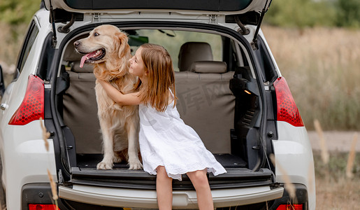 青春期前的女孩与金毛猎犬在汽车后备箱