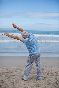 在沙滩上做伸展运动的老人