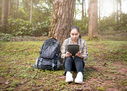 暑假期间，年轻女性旅行者在自然小径上通过平板电脑搜索 GPS 坐标。