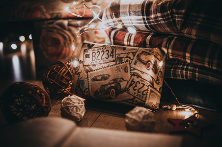装在盒子里并用节日纸包裹的礼物躺在圣诞树下，在 LED 花环发出的温暖灯光下。