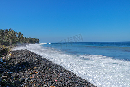 小手点击效果摄影照片_有黑色鹅卵石的热带海滩。