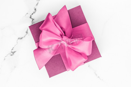 大理石背景丝绸蝴蝶结粉色礼盒、女婴送礼会礼物和豪华美容品牌的魅力时尚礼物、假日平底艺术设计
