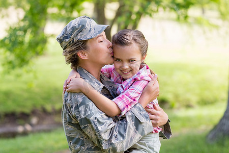 部队女兵摄影照片_快乐的女兵在公园亲吻她的女儿