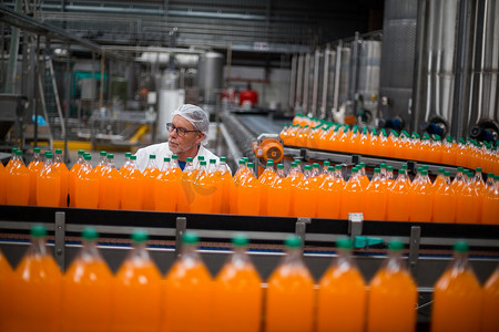 工厂工程师监控生产线上的灌装果汁瓶