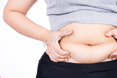 健身背景摄影照片_胖女人持有过多的脂肪腹部，超重的脂肪腹部隔离在白色背景。