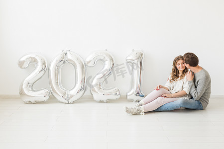 假期、节日和派对概念 — 幸福的情侣拿着白色背景的 2021 年银色气球。