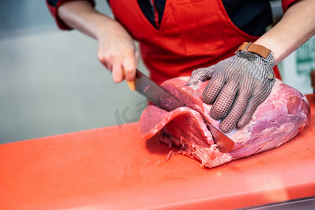 戴着金属安全网手套在肉店切鲜肉的妇女