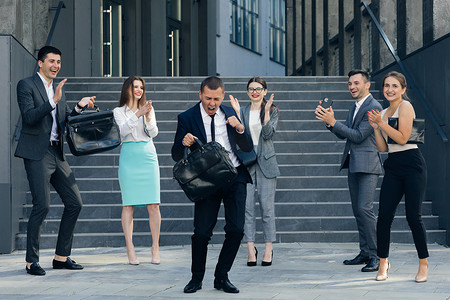 年轻快乐的业务经理穿着西装和领带从办公楼跳舞。
