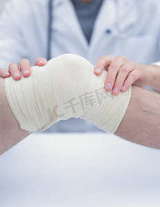 理疗医生摄影照片_创伤科医生，在膝盖上包扎绷带