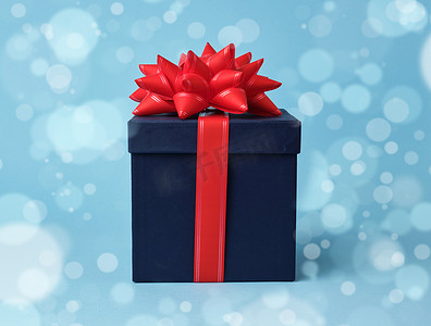 礼物的方形蓝色纸板箱和蓝色的丝绸红色蝴蝶结