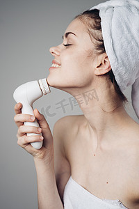 头上戴毛巾的妇女面部按摩器皮肤护理卫生