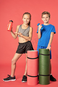 鼠年拜年海报摄影照片_红色背景下拿着运动器材的可爱孩子