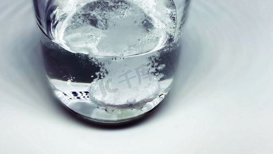 泡腾片落入装满水的玻璃杯中。