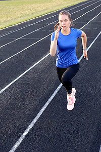 跑步运动员在田径跑道上跑步，在体育场训练她的有氧运动。