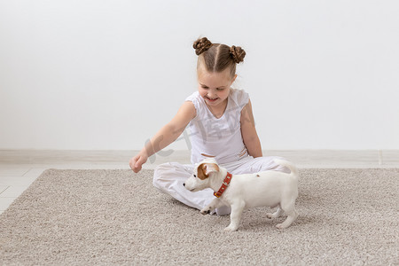 宠物、儿童和动物概念 — 可爱的小女孩和有趣的小狗玩得开心