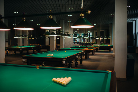 台球俱乐部里有绿色表面和球的台球桌。
