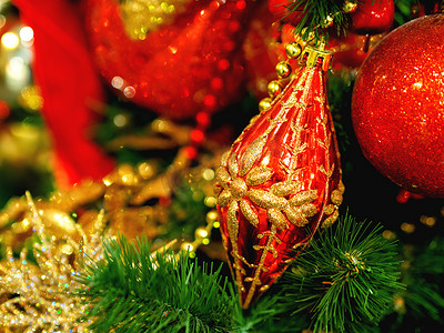 金色装饰品摄影照片_新年红色装饰与圣诞树上的金色装饰品。