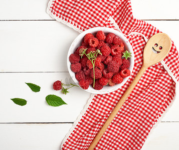 木板桌上白色木盘中成熟的红树莓