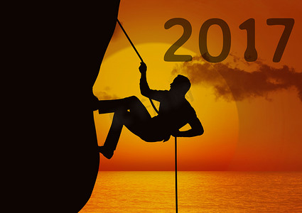 2017 年合成图像与男子使用绳索攀登悬崖的剪影