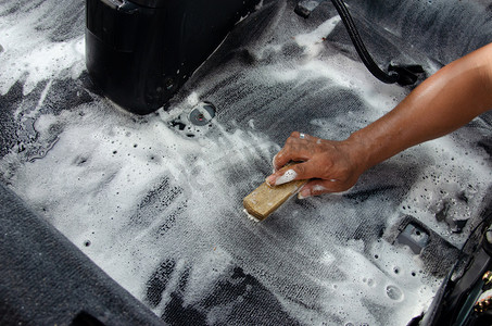 清洗汽车地毯。现代汽车内部的细节。用刷子和清洁液清洁汽车地毯。