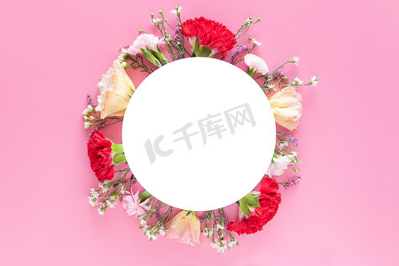 用鲜艳的粉红色背景上带有白色圆圈横幅标签的新鲜五颜六色的春天花朵制作的创意布局。