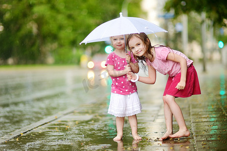 雨中街道摄影照片_两个可爱的小姐妹在雨中玩得开心
