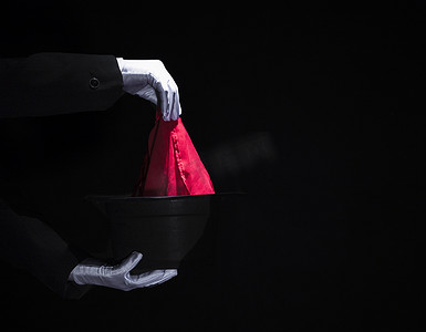 魔术师的手用餐巾纸顶黑帽子表演魔术。