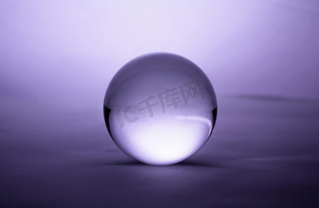 紫色渐变背景上透明的水晶玻璃球球体。