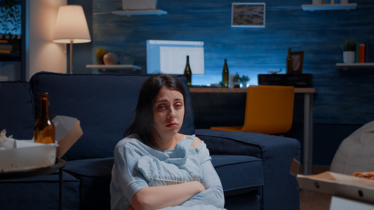不快乐的抑郁女人抱着枕头坐在地板上哭泣的视角