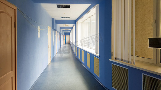 乌克兰，基辅 — 2019年9月24日：一家有蓝色墙壁、木门和窗户的医院里，空荡荡的长走廊里没有人。