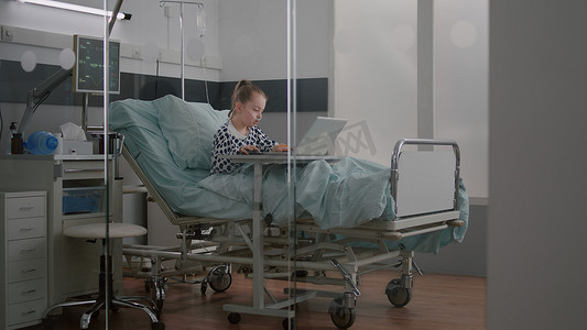 生病的孩子在体检期间在床上放松地在笔记本电脑上玩卡通视频游戏