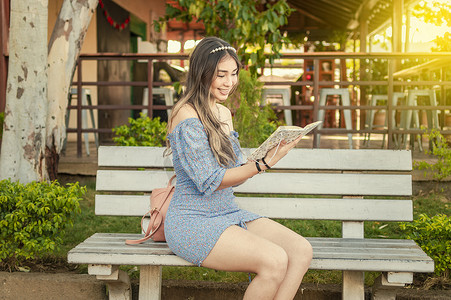 一个女生摄影照片_一个可爱的女孩坐在长凳上读书，年轻漂亮的拉丁女孩在长凳上读书