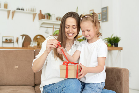 快乐的女儿和母亲打开礼物并大笑。