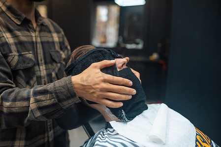 理发师在理发店准备用热毛巾剃须的男人脸
