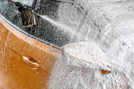 黄色的汽车后视镜完全覆盖着厚厚的洗发水泡沫，在洗车时清洗时，更多的是从刷子上喷洒的。