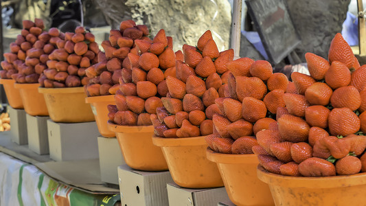 印度孟买街头户外果蔬零售市场的摊位上堆放着一堆鲜红的草莓樱桃