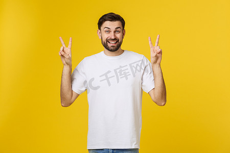 年轻英俊的男子穿着条纹 T 恤，背景是孤立的黄色，微笑着看着镜头，手指做着胜利的手势。