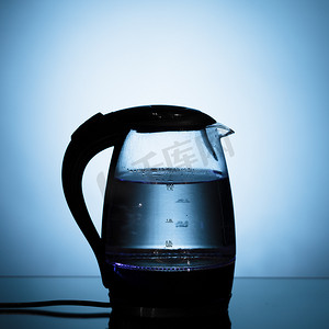 蓝色水煮摄影照片_蓝色背景上的电玻璃水壶