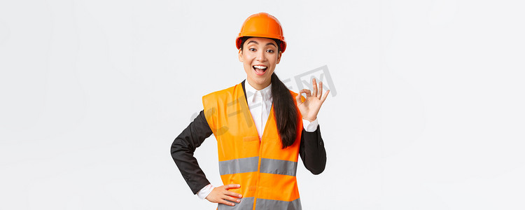 满意的快乐亚洲女工程师、戴着安全帽和反光夹克的施工经理表现出良好的姿态很高兴，保证建筑质量，确保一切都出色