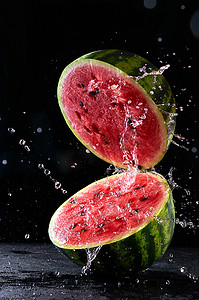 水花摄影照片_成熟的西瓜被切成两半，水花在空中飞舞