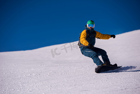 冬天骑行摄影照片_滑雪板跑下斜坡并自由骑行